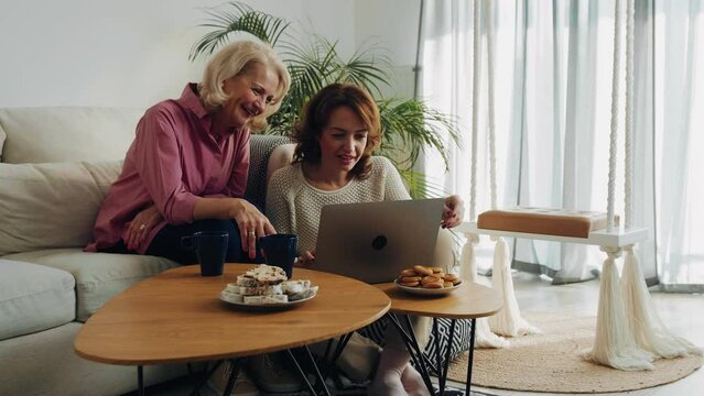 Senior friends at home browsing internet on laptop