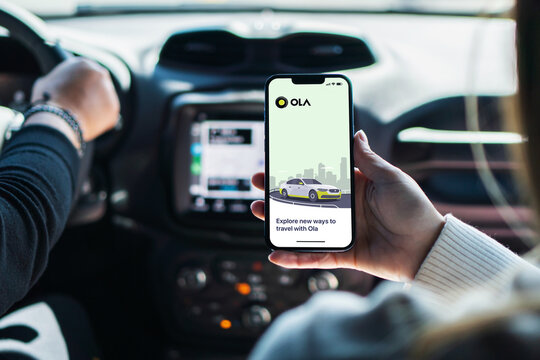 Girl inside car holding smartphone with Ola Cabs app on screen. Rio de Janeiro, RJ, Brazil. August 2022