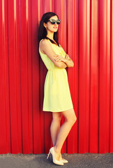 Portrait of beautiful brunette young woman wearing yellow dress on red background