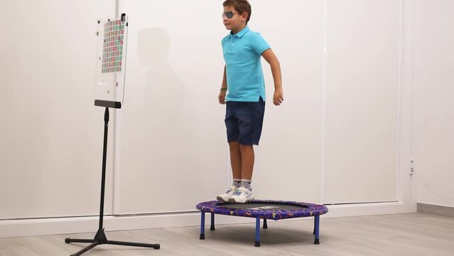 A child receives vision therapy with hart cards while bouncing on a rug.