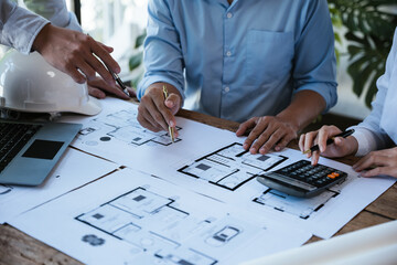 Close up of hands working calculate and brainstorming on paperworks and floor plan drawings about design architectural and engineering for houses and buildings.