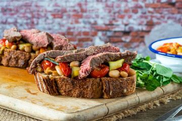 Beef steak on sourdough with garlicky tomatoes, courgettes and cannellini beans