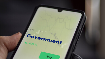 An investor's analyzing the government etf fund on screen. A phone shows the gov ETF's to invest