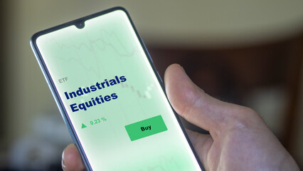 An investor's analyzing the industrials equities etf fund on screen. A phone shows the ETF's prices industry equity to invest