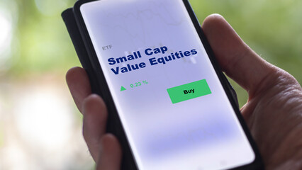 An investor's analyzing the small cap value equities etf fund on screen. A phone shows the small cap value equities to invest, texte in English.
