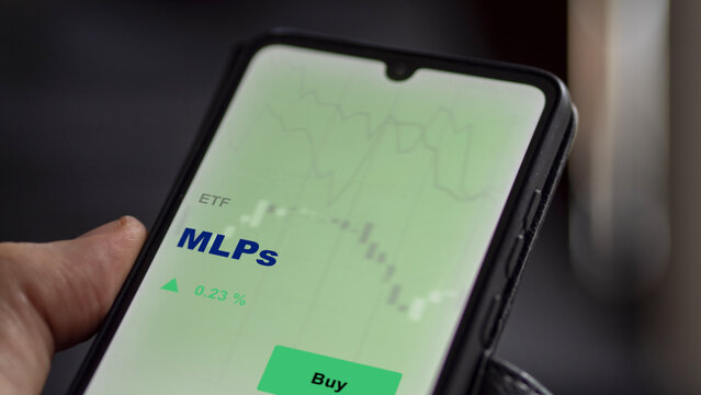 An investor's analyzing the MLPs etf fund on screen. A phone shows the ETF's prices mlp stocks to invest
