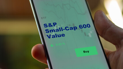 An investor's analyzing the derivative income etf fund on screen. A phone shows the ETF's prices...