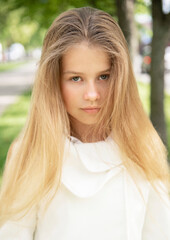 portrait of a little  beautiful  girl with long blond hair in the green park on sunny spring day