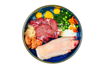 Natural raw organic dog food in bowl on white. Fresh meat, pork leg, minced fish, quail eggs, vegetables.