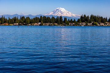 kayakers on blue colored water of Lake Tapps with snow capped Mt. Rainier on the background.