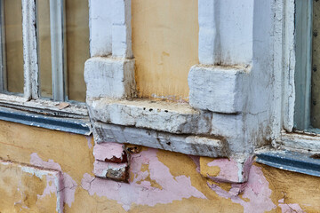 fragment of the wall of an old house with windows and peeling paint