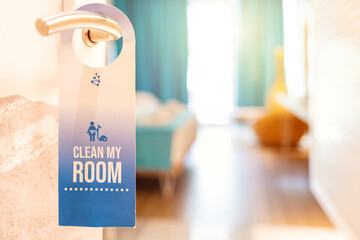 Hotel room with label on a door handle. Door of hotel room with ''clean my room'' sign. Closed door...