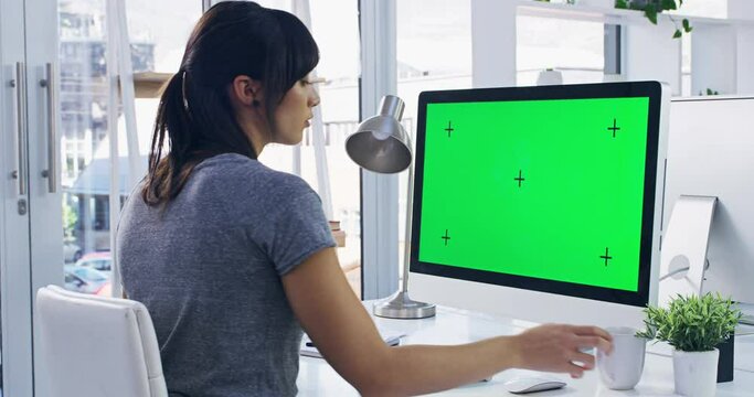 Business woman working on green screen computer with chroma key while drinking tea or coffee and writing notes. Busy worker typing on desktop advertising mockup space while sitting at a office table