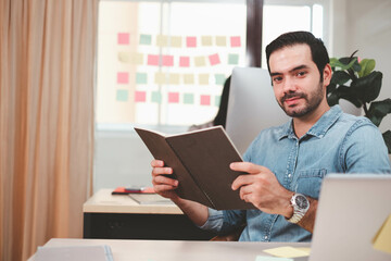 Portrait of serious businessman with laptop sitting at desk in office. Cheerful casual caucasian employee, Handsome businessman using mob phone. successful business working at office. mobile phone.