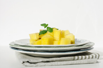 Pieces of ripe yellow watermelon and mint on vintage plates and white background