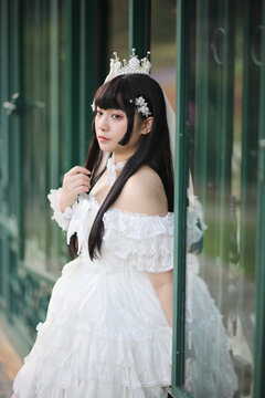 Beautiful young woman with white lolita dress with european garden Japanese fashion