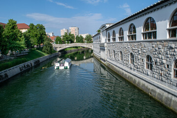 Naklejka premium The Ljubljanica River flows past Plečnik's Market toward the residential area of Ljubljana