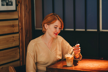 Woman drinking iced coffee cappuccino or latte in the cafe sitting next to the table with low...