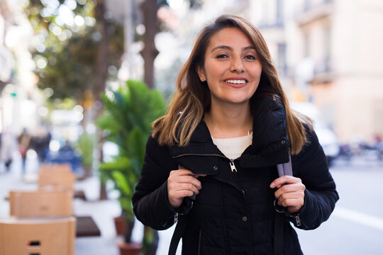 Young hispanic woman on blurred city street background