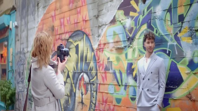 Photographer making photo of a young man in suit on a graffiti wall background. Action. Photo shooting and street art.