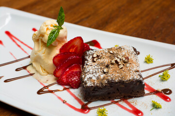 Chocolate brownie dessert with strawberries and ice cream