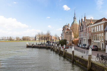 Obraz premium Canal houses with the dome of the medieval city gate on the quay in the background, in the old part of the historic city of Dordrecht.