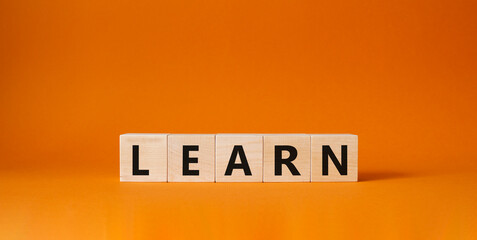 Learn symbol. Wooden cubes with word Learn. Beautiful orange background. Learn concept. Copy space.