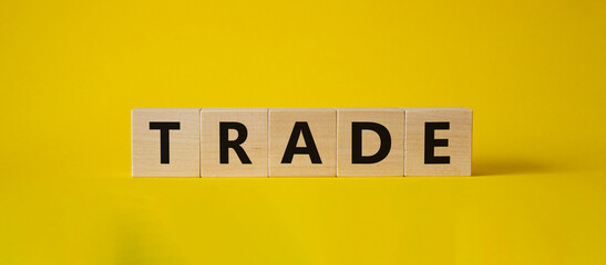 Trade symbol. Wooden cubes with word Trade. Beautiful yellow background. Trade concept. Copy space.