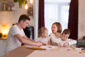 Obraz na płótnie Canvas happy family dad, mom and two kids make Christmas cookies and have fun together at home in the kitchen. Children siblings making homemade xmas gingerbreads