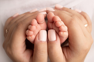 Mother is doing massage on her baby foot. Closeup baby feet in mother hands. Prevention of flat feet, development, muscle tone, dysplasia. Family, love, care, and health concepts. Studio macro. 