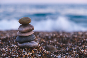 Pyramid of pebbles on the beach at sunset. Concept of zen, stability, harmony, balance and meditation, copy space. 
