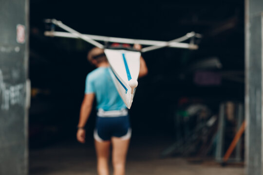 Sportsman single scull man rower prepare to competition carry boat on shoulder with muscular hand
