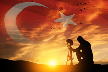 Silhouette of soldier kneeling with his head bowed against the sunrise or sunset and Turkey flag. Concept of crisis of war and conflicts. Greeting card for Turkish Armed Forces Day, Victory Day.