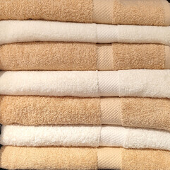 Fototapeta na wymiar white and beige clean folded towels of cotton stacked in a laundry or a spa with soft texture
