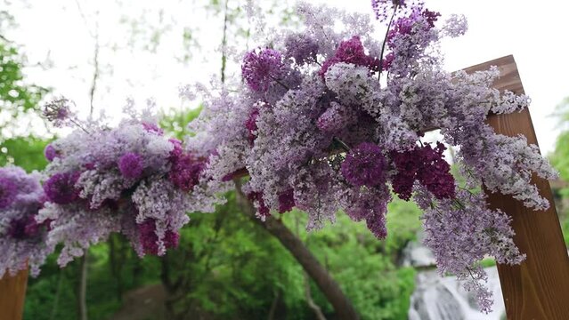 decor of the arch for the wedding ceremony with lilac flowers near waterfall