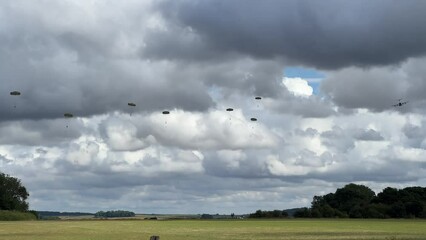 Royal Air Force Airbus A400M Atlas military plane (RAF ZM414) flying low level dropping 3 PARA parachute regiment soldiers on an airborne assault military exercise, summer bright cloud sky