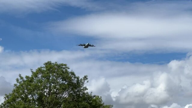 Royal Air Force Airbus A400M Atlas military plane (RAF ZM414) flying low level dropping 3 PARA parachute regiment soldiers on an airborne assault military exercise, summer bright cloud sky