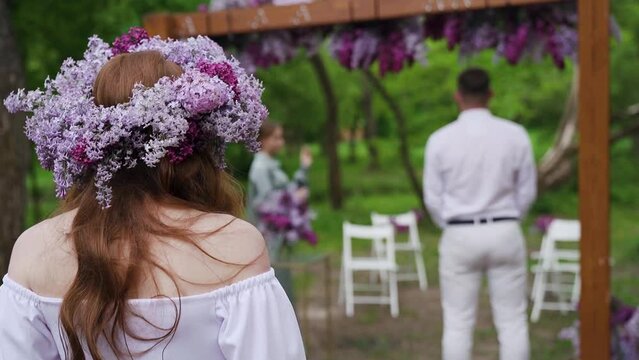 Beautiful Bride in lilac wreath Going Down the Aisle, while Groom Waits at arch