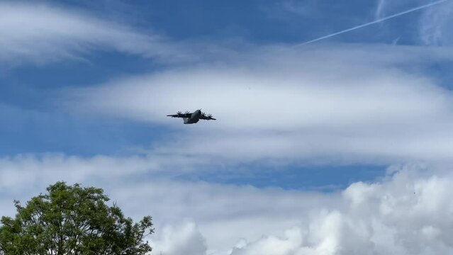 Royal Air Force Airbus A400M Atlas military plane (RAF ZM414) flying low level dropping 3 PARA parachute regiment soldiers on an airborne assault military exercise, summer bright cloud sky