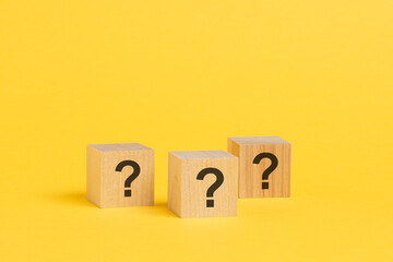 front view on wood cubes with question marks. many question arising concept, yellow background