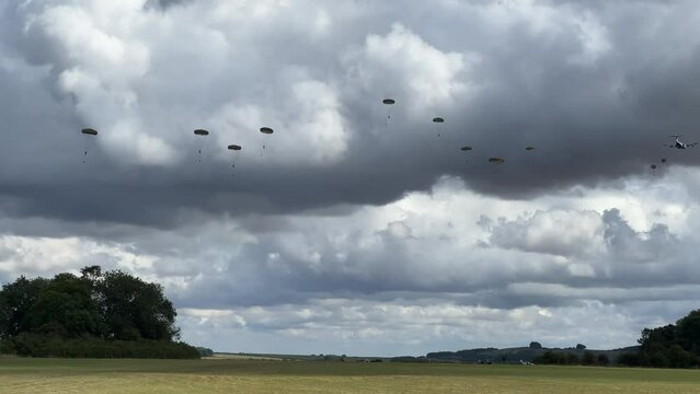 Royal Air Force Airbus A400M Atlas military plane (RAF ZM414) flying low level dropping 3 PARA parachute regiment soldiers on an airborne assault military exercise, summer bright cloud sky