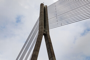 Fototapeta na wymiar Cable-stayed bridge concrete support and cables on sky background