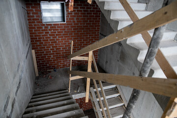 Obraz premium Scaffold and temporary access stairs erected on new housing development construction site around new multi-storey house to allow cladding, windows and roof installation