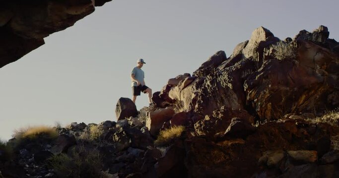 Man climbs along roch arch in the Mojave Desert, California