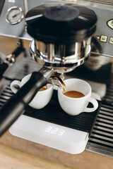 Coffee flows out of the holder into two mugs. Coffee making concept.