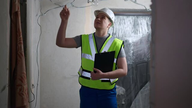 Medium shot portrait of concentrated thoughtful architect in hard hat with paperwork standing in new flat looking around. Expert professional Caucasian man planning renovation and repair indoors