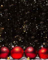 Christmas decorations composition view of four red evening balls with red glitter snowflakes on it on dark background with silver and gold colors bokeh. Holiday concept with copy space on top.