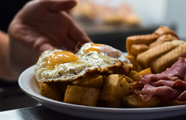 Hand of kitchen employee putting plate ready with breakfast eggs order on counter