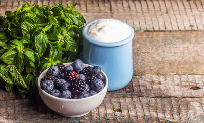 A jar of homemade yogurt and a bowl of berries. Blueberries and yogurt