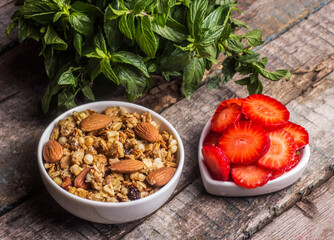 Muesli with almonds in a white bowl and strawberries. Useful homemade breakfast